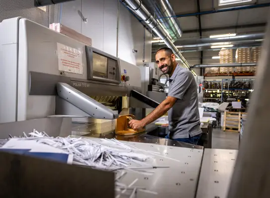 Un technicien souriant devant sa machine de façonnage.